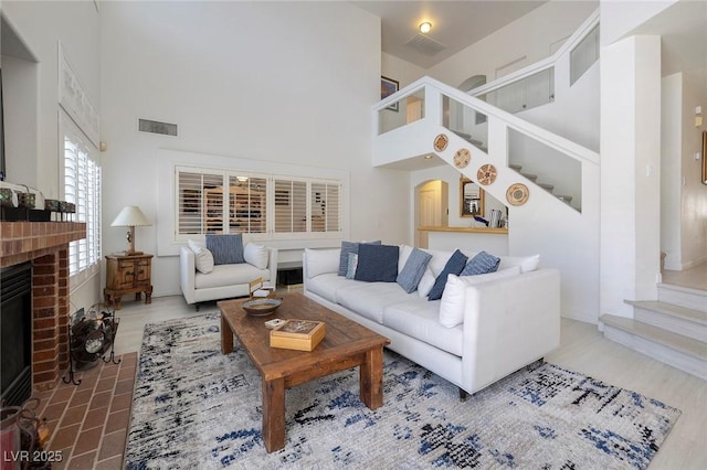 living room featuring hardwood / wood-style flooring, a towering ceiling, and a fireplace