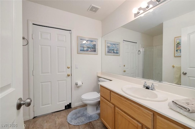 bathroom with a shower with door, vanity, wood-type flooring, and toilet