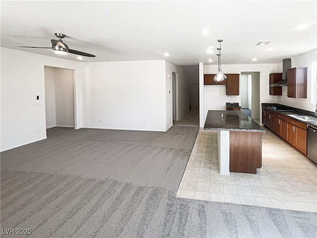 kitchen with a kitchen island, light carpet, dark stone countertops, wall chimney range hood, and pendant lighting