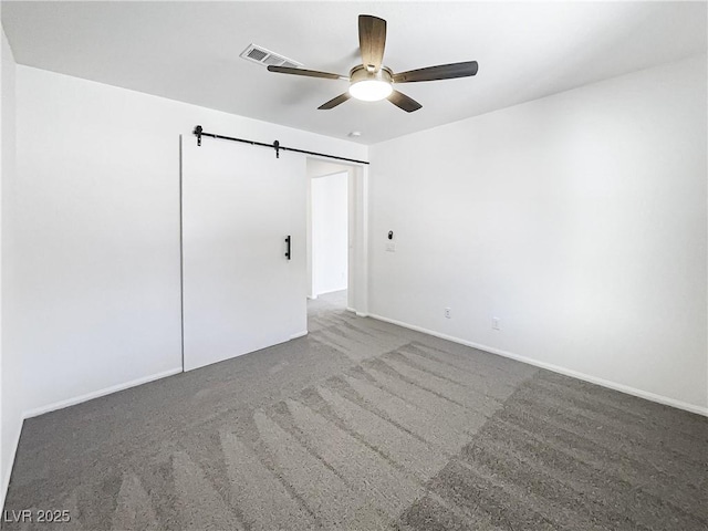 unfurnished bedroom with ceiling fan, a barn door, and carpet flooring