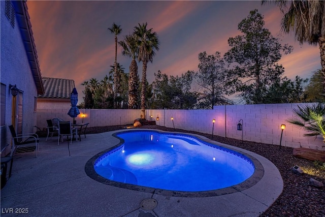 pool at dusk featuring a patio area