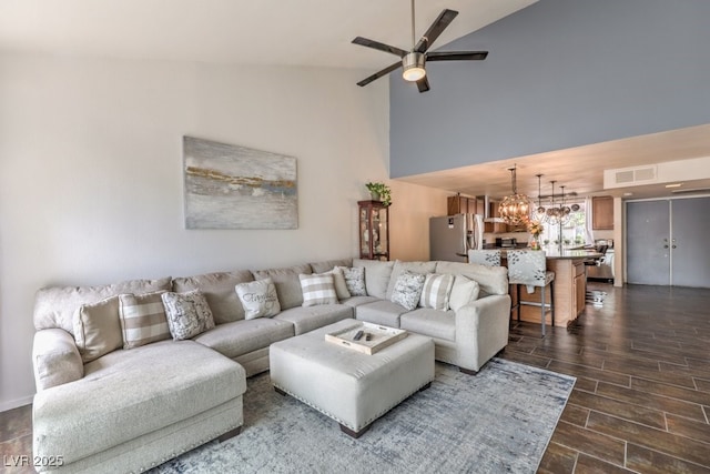 living room featuring high vaulted ceiling and ceiling fan with notable chandelier