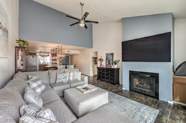 living room featuring high vaulted ceiling and ceiling fan with notable chandelier