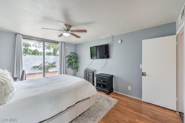 bedroom featuring wood-type flooring, access to exterior, a textured ceiling, and ceiling fan