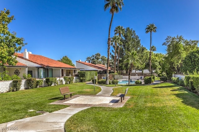 view of home's community with a pool and a lawn