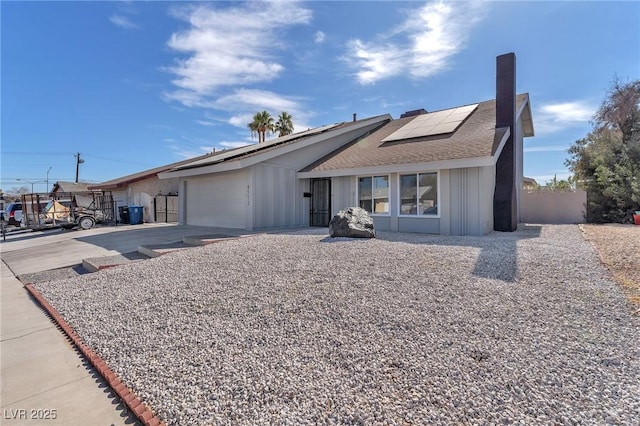 ranch-style house with a garage and solar panels