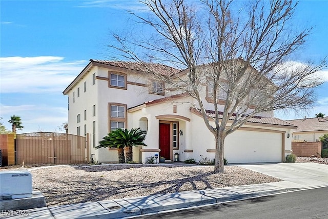 mediterranean / spanish-style home with stucco siding, concrete driveway, a gate, fence, and a garage