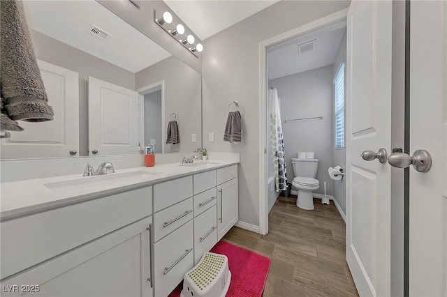 full bathroom with hardwood / wood-style flooring, vanity, shower / tub combo, and toilet