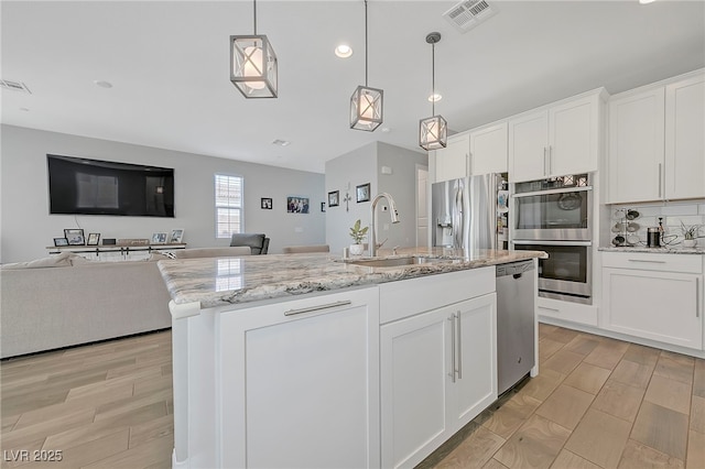 kitchen with sink, hanging light fixtures, white cabinets, and appliances with stainless steel finishes