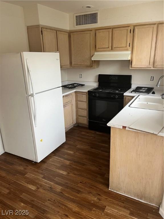 kitchen featuring dark hardwood / wood-style flooring, black range with gas stovetop, light brown cabinets, and white refrigerator