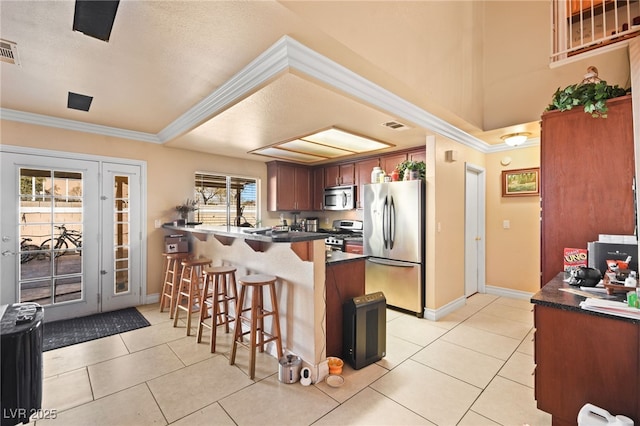 kitchen with crown molding, appliances with stainless steel finishes, kitchen peninsula, and light tile patterned flooring