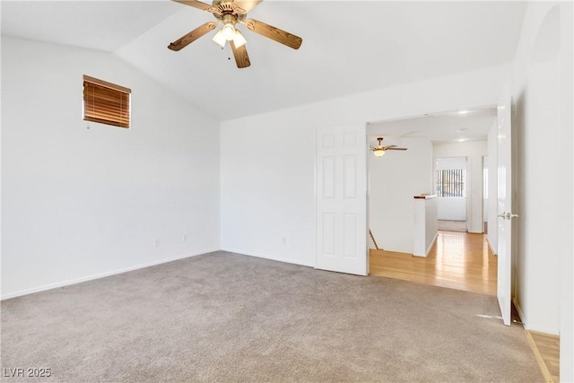 carpeted spare room featuring vaulted ceiling and ceiling fan