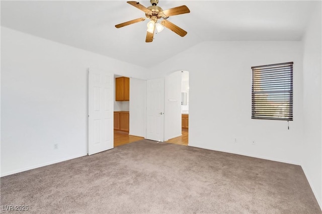 carpeted empty room with vaulted ceiling and ceiling fan