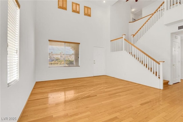 unfurnished living room with light hardwood / wood-style flooring and a high ceiling