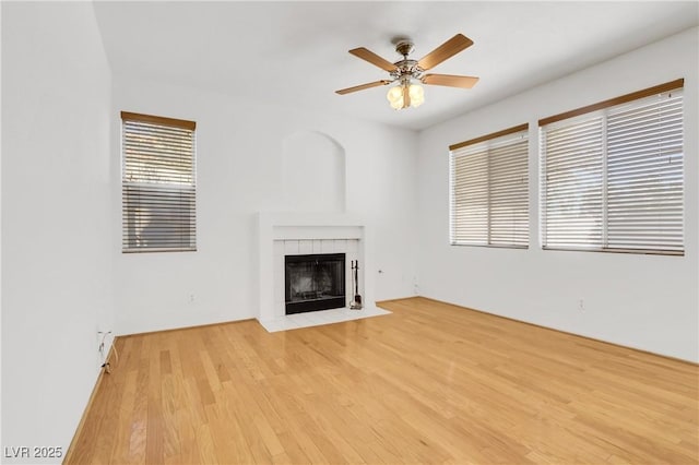 unfurnished living room featuring ceiling fan, a tile fireplace, and light hardwood / wood-style flooring