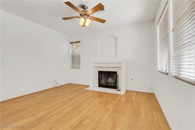 unfurnished living room featuring ceiling fan, a fireplace, and light hardwood / wood-style flooring