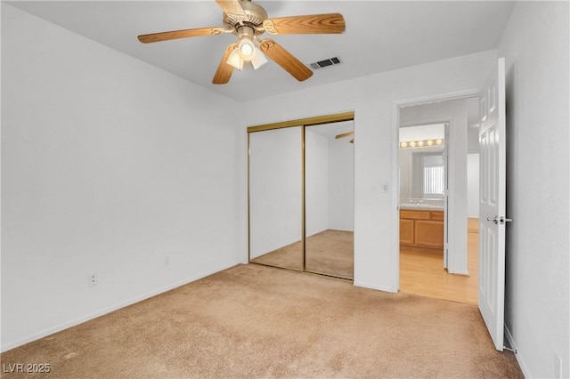 unfurnished bedroom featuring ceiling fan, a closet, and light carpet