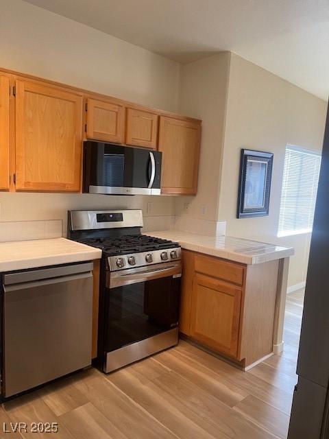 kitchen featuring stainless steel appliances, light wood-type flooring, and kitchen peninsula