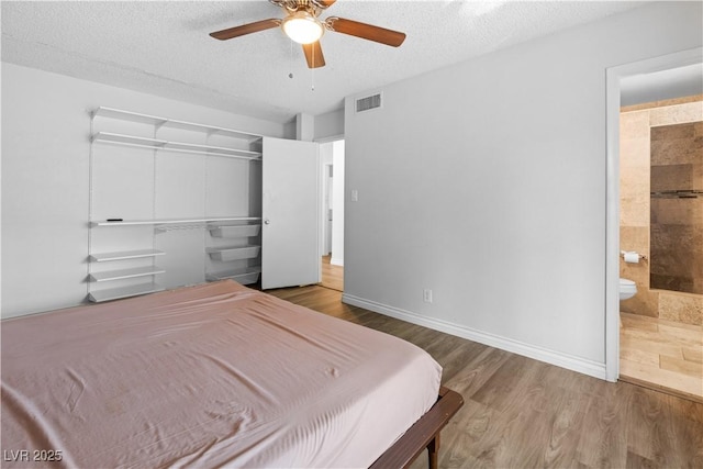 bedroom with ceiling fan, connected bathroom, wood-type flooring, a textured ceiling, and a closet