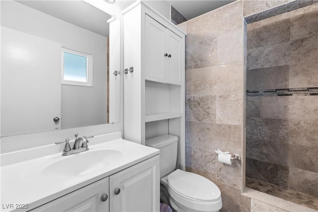 bathroom with vanity, toilet, and a tile shower