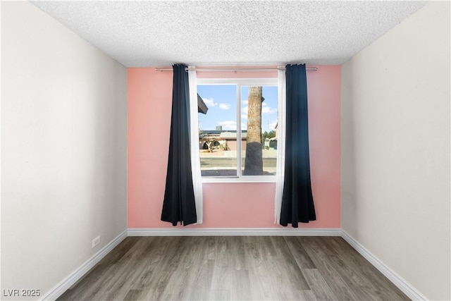 unfurnished room featuring hardwood / wood-style flooring and a textured ceiling