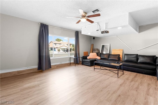 living room featuring ceiling fan, a textured ceiling, and light wood-type flooring