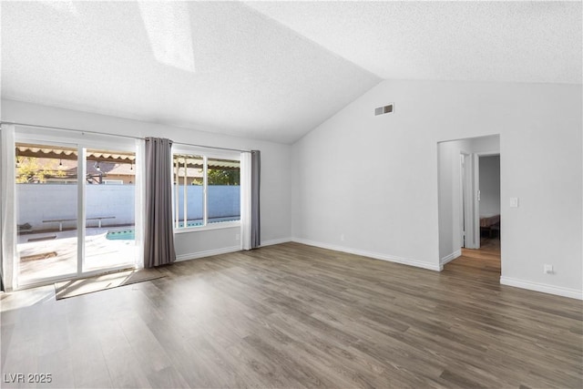 empty room featuring lofted ceiling, a textured ceiling, and dark hardwood / wood-style flooring