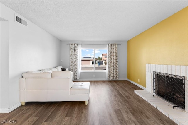 unfurnished living room featuring a brick fireplace, wood-type flooring, and a textured ceiling