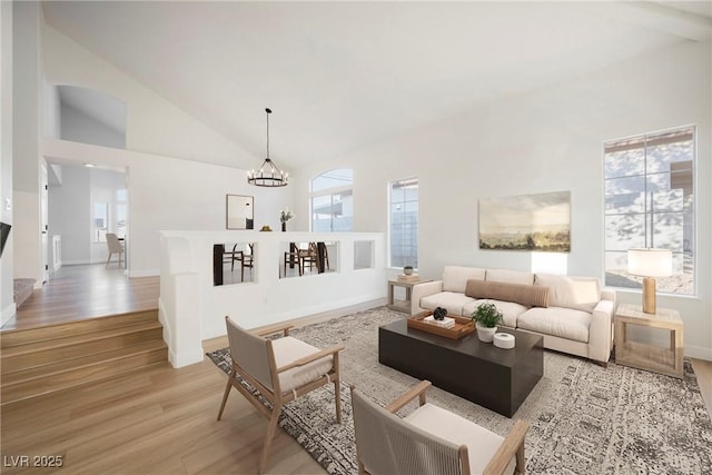 living room with wood-type flooring, high vaulted ceiling, and an inviting chandelier