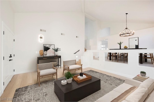 living room with high vaulted ceiling, a notable chandelier, and light hardwood / wood-style floors