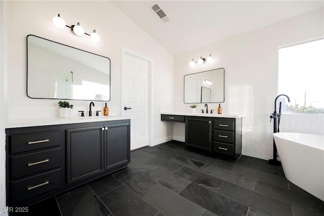 bathroom with vaulted ceiling, vanity, and a tub to relax in