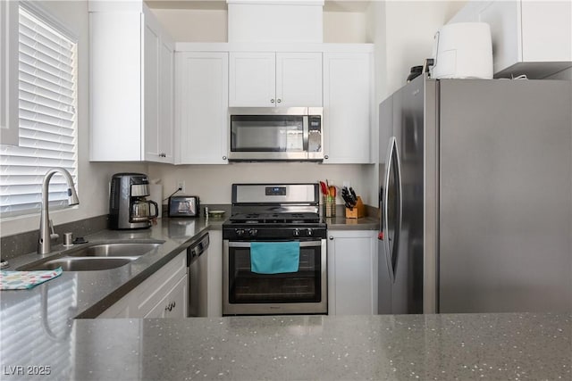 kitchen featuring white cabinetry, sink, stainless steel appliances, and dark stone counters