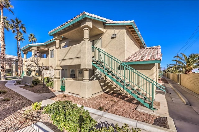 view of property featuring stairs and fence