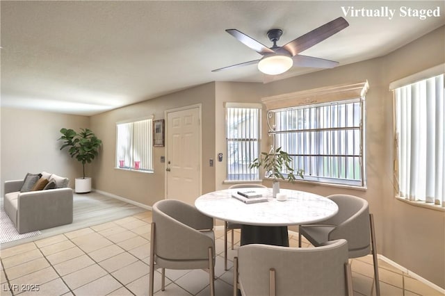 tiled dining room featuring ceiling fan and baseboards