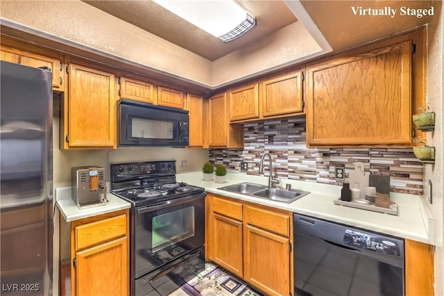 kitchen with light countertops, a sink, black appliances, and decorative backsplash