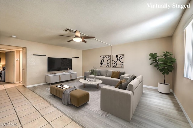 living area with visible vents, baseboards, light wood-style flooring, and ceiling fan