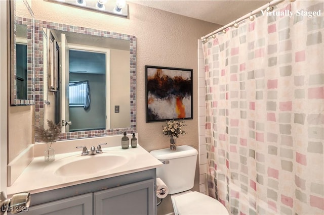 full bath featuring toilet, curtained shower, vanity, and a textured wall
