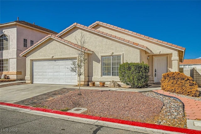 view of front facade with an attached garage, a tile roof, concrete driveway, and stucco siding