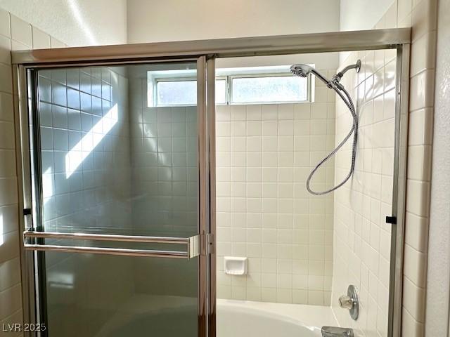 bathroom featuring combined bath / shower with glass door