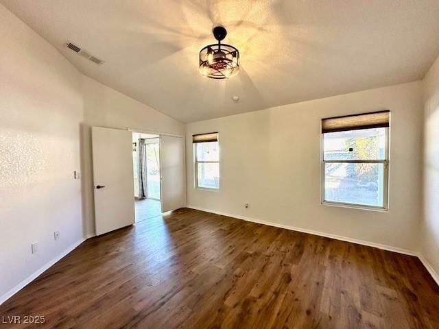 empty room featuring lofted ceiling, dark hardwood / wood-style flooring, and a wealth of natural light