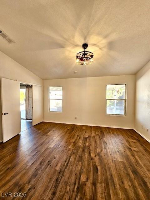 empty room featuring dark hardwood / wood-style flooring, vaulted ceiling, and a textured ceiling