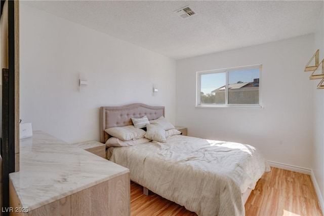 bedroom featuring light hardwood / wood-style flooring and a textured ceiling