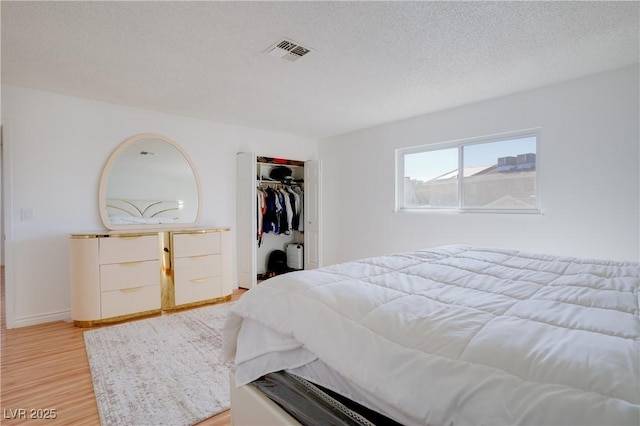 bedroom with a closet, light hardwood / wood-style floors, and a textured ceiling