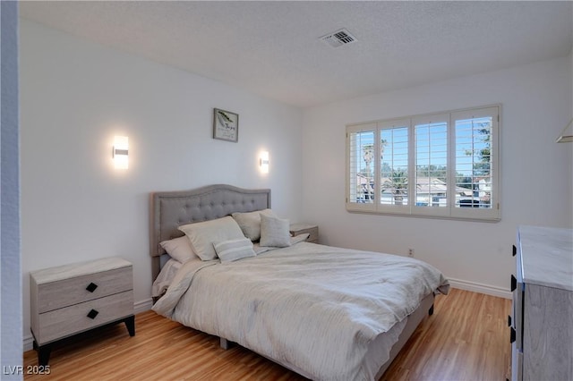 bedroom with light hardwood / wood-style floors and a textured ceiling