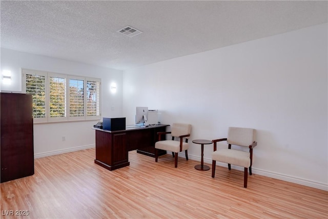 home office with a textured ceiling and light wood-type flooring