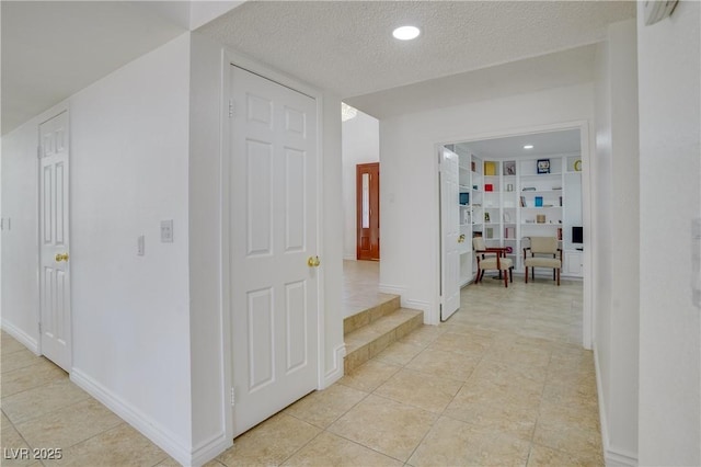 hallway featuring light tile patterned floors and a textured ceiling