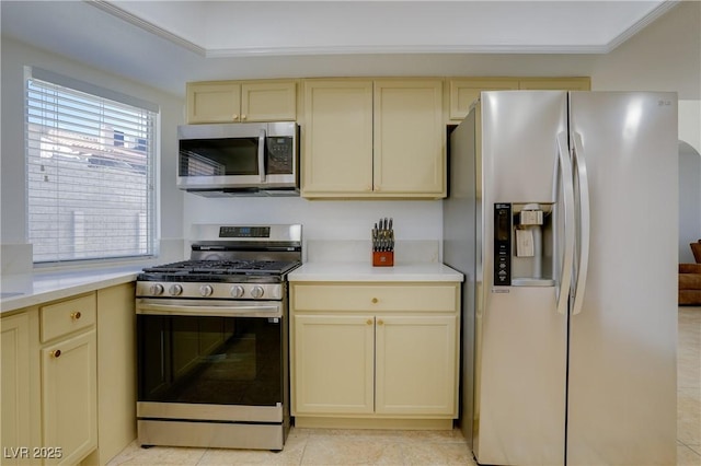 kitchen with appliances with stainless steel finishes, cream cabinets, and light tile patterned floors