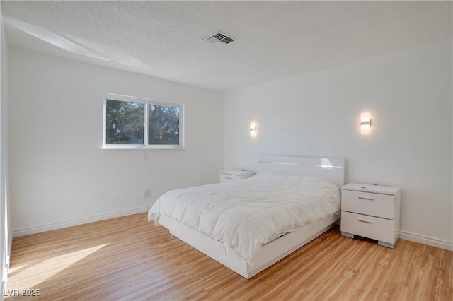 bedroom with a textured ceiling and light wood-type flooring