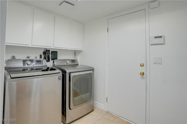 laundry room with cabinets, washing machine and dryer, and light tile patterned flooring