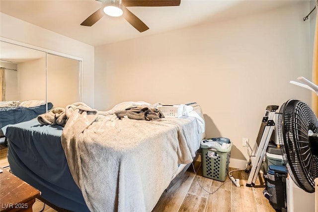 bedroom featuring a closet, baseboards, a ceiling fan, and light wood finished floors